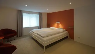 a bedroom with a bed and a window and a chair at Alte Metzg - Hostel in Appenzell