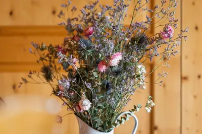 a white vase with a bunch of flowers in it at Vegan Health Hotel Sonnenberg in Schwellbrunn