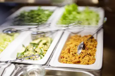 a buffet of food in plastic trays with vegetables at Vegan Health Hotel Sonnenberg in Schwellbrunn