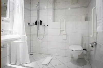 a white bathroom with a shower and a toilet at Vegan Health Hotel Sonnenberg in Schwellbrunn