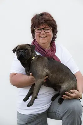 a woman holding a pug dog on her lap at BNB Claudia in Appenzell