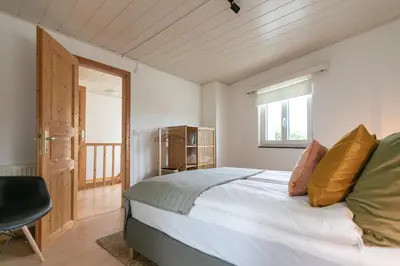 a bedroom with a bed and a chair and a window at INN JOY Apartments - Sankt Gallen West in St. Gallen