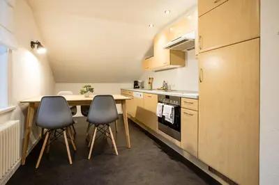 a small kitchen with a wooden table and two chairs at INN JOY Apartments - Sankt Gallen West in St. Gallen