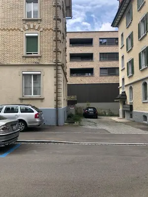 a parking lot with cars parked in front of a building at INN JOY Apartments - Sankt Gallen Lachen in St. Gallen