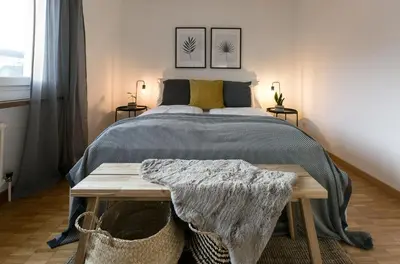 a bedroom with a bed with a table and two pictures at INN JOY Apartments - Rorschach mit Panoramasicht in Rorschach