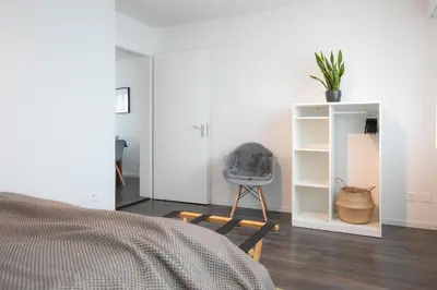 a bedroom with a bed and a chair and a shelf at INN JOY Apartments - Rorschach mit Panoramasicht in Rorschach