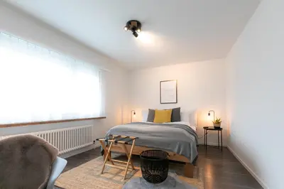 a bedroom with a bed and a chair and a window at INN JOY Apartments - Rorschach mit Panoramasicht in Rorschach