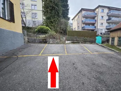 an empty parking lot with a red arrow next to a building at RUSTICO INN - SIMPLE ROOMS -- OLMA Messen & Autobahn 1 Min, HSG 6 Min, Spital 7min, günstige Parkplätze in St. Gallen