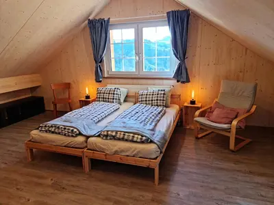a bedroom with a bed and a chair in a attic at Grosses Ferienhaus für traumhafte Familienferien im Appenzellerland in Speicher