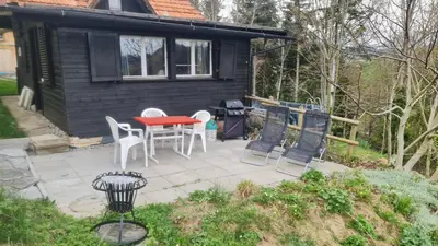a patio with a red table and white chairs at Grosses Ferienhaus für traumhafte Familienferien im Appenzellerland in Speicher