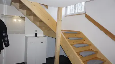 a wooden staircase in a room with white walls at Loft in der Natur mit Gartenzugang und Sauna in Herisau