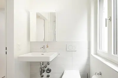a white bathroom with a sink and a mirror at VISIMO Apartments Mühlensteg St Gallen - Elegant Quiet Central in St. Gallen