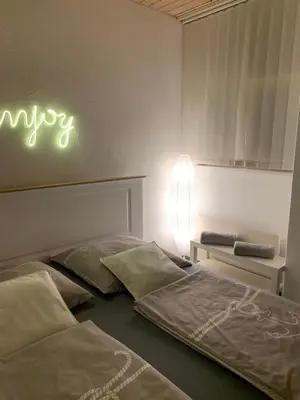 a bedroom with two beds and a neon sign on the wall at Guest room David 11 in St. Gallen