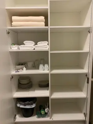 a white closet with white shelves and plates and towels at Guest room David 11 in St. Gallen