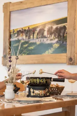 a person cutting a cake on a table with a painting at Gasthaus Rössli in Brülisau