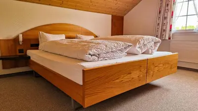a bedroom with a large bed with a wooden headboard at Gasthaus Rössli in Brülisau