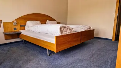 a bedroom with a large bed with a wooden headboard at Gasthaus Rössli in Brülisau