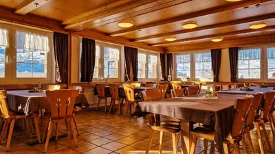 a dining room with tables and chairs and windows at Gasthaus Rössli in Brülisau