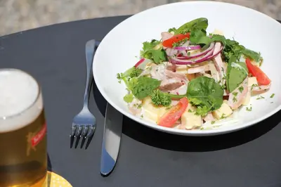 a plate of food with a salad and a glass of beer at Militärkantine St. Gallen in St. Gallen