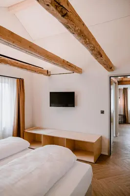 two beds in a room with a tv on the wall at Hotel Müllers - Self-Check-in in Arbon