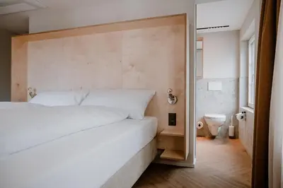 a bedroom with a large white bed and a bathroom at Hotel Müllers - Self-Check-in in Arbon
