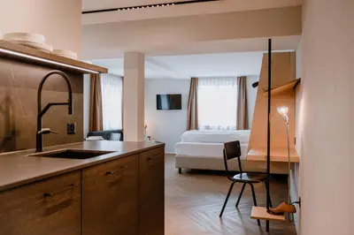 a kitchen with a sink and a bedroom with a bed at Hotel Müllers - Self-Check-in in Arbon