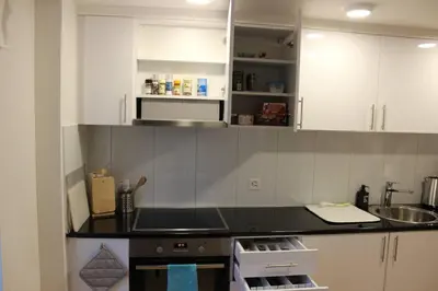 a kitchen with white cabinets and a black counter top at Casa Schilling 2,5 rooms in St Gallen, modern, quiet and close to the center in St. Gallen