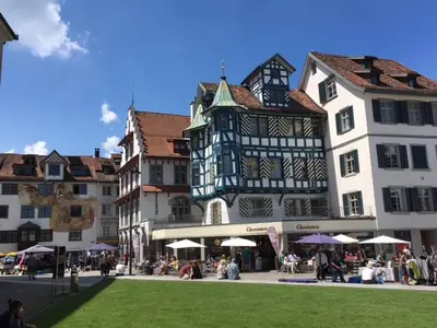 a group of buildings with people sitting outside of them at Casa Schilling 2,5 rooms in St Gallen, modern, quiet and close to the center in St. Gallen