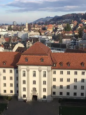 a large white building with a red roof in a city at 2 rooms with balcony, central, quiet location in St. Gallen