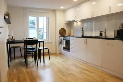 a kitchen with white cabinets and a table and chairs at Completely renovated apartment near the train station and the center in St. Gallen