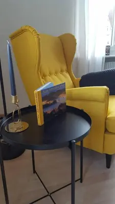 a book on a table in front of a yellow couch at Casa Schilling- 2,5 rooms with balcony near hospital, university in St. Gallen