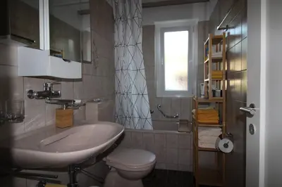 a bathroom with a sink and a toilet and a window at Casa Schilling- 2,5 rooms with balcony near hospital, university in St. Gallen
