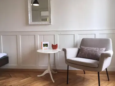 a chair and a table in a room with a mirror at Casa Schilling - 4 charming rooms in the best location in St. Gallen