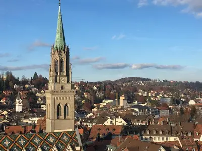 a church steeple with a clock tower in a city at Nice apartment with sun terrace in St. Gallen