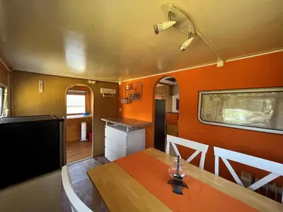 a dining room with an orange wall and a table at Camping Schönengrund in Schönengrund