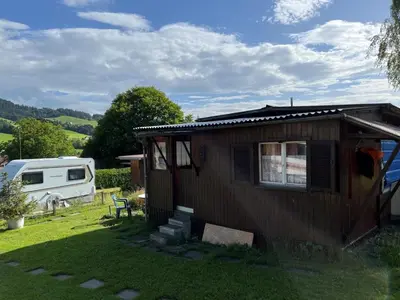 a small house in a yard with a trailer at Camping Schönengrund in Schönengrund