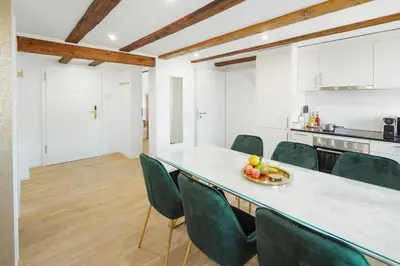 a kitchen with a table with chairs and a bowl of fruit at VISIMO Apartments Steigerstrasse St Gallen - Modern Living near OLMA & Hospital in St. Gallen