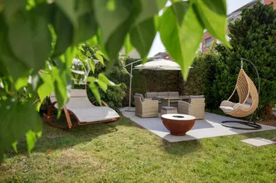 a garden with two chairs and an umbrella at VISIMO Apartments Steigerstrasse St Gallen - Modern Living near OLMA & Hospital in St. Gallen