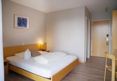 a bedroom with a white bed and a chair at Hotel Garni Arnegg in Arnegg