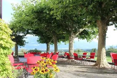a group of red chairs and tables under trees at Hotel Restaurant Schlössli Sax in Sax