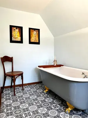 a bathroom with a large tub and a chair at Villa Bergruh in St. Gallen