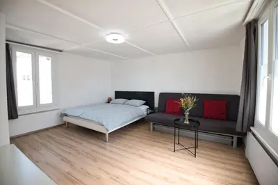 a bedroom with a bed and a couch and a table at Lake Getaway Apartment with Private entrance, right on the Lake Constance cycle path, barbecue area, free wifi, Netflix and free bikes in Salmsach