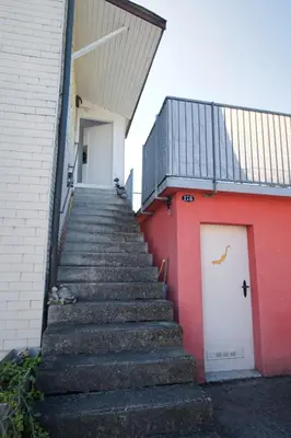a staircase leading up to a red building with a white door at Lake Getaway Apartment with Private entrance, right on the Lake Constance cycle path, barbecue area, free wifi, Netflix and free bikes in Salmsach