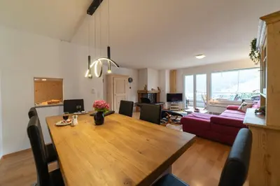 a dining room and living room with a wooden table at Vista Montagna in Unterwasser