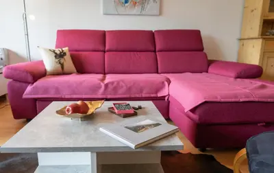 a living room with a pink couch and a table at Vista Montagna in Unterwasser