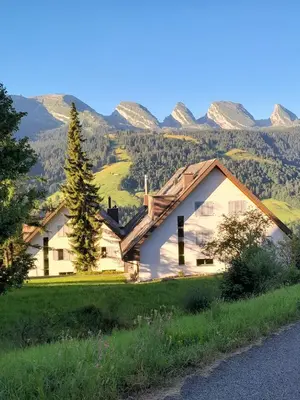 a house on a hill with mountains in the background at Vista Montagna in Unterwasser