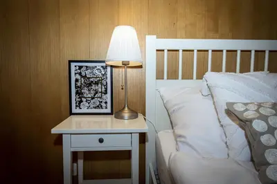 a lamp on a night stand next to a bed at Capanna in Wildhaus