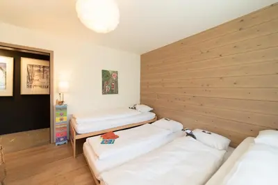 a room with three beds and a wooden wall at Primula in Wildhaus