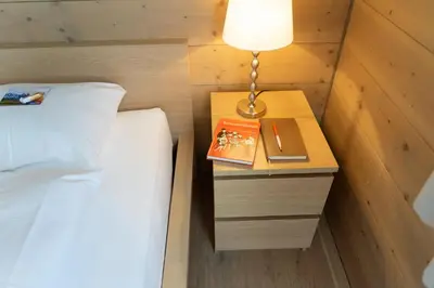 a bedroom with a bed and a table with a lamp and a book at Primula in Wildhaus