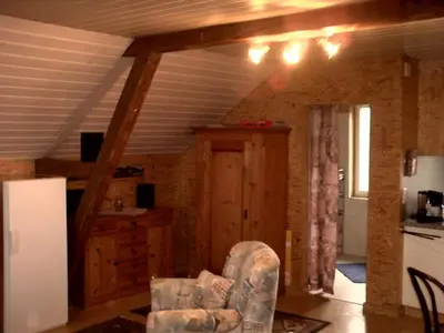 a living room with a chair and a kitchen at Appartement Unterstädeli Engelburg SG in Wittenbach